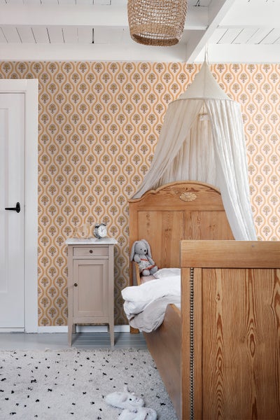 Kinderzimmer mit gemusterten Tapeten, Holzmöbeln und Baldachin über dem Bett