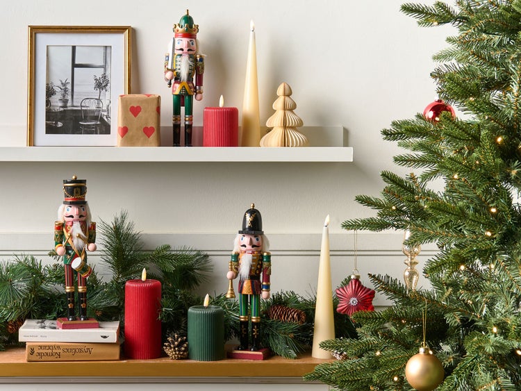 Weihnachtliche Dekoration mit Nussknackern, Kerzen und geschmücktem Weihnachtsbaum