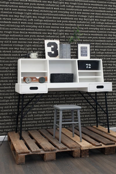 Schreibtisch mit Regalen und Schubladen, kombiniert mit einem grauen Hocker auf einer Holzpalette