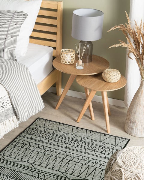 Schlafzimmer mit Bett, Nachttischen, Lampe, Teppich und Dekorationsartikeln.