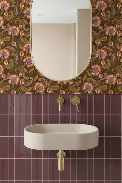 Modernes Badezimmer mit floraler Mustertapete, ovalem Spiegel, vertikalen lila Fliesen, beigem Waschbecken und goldfarbenen Armaturen.
