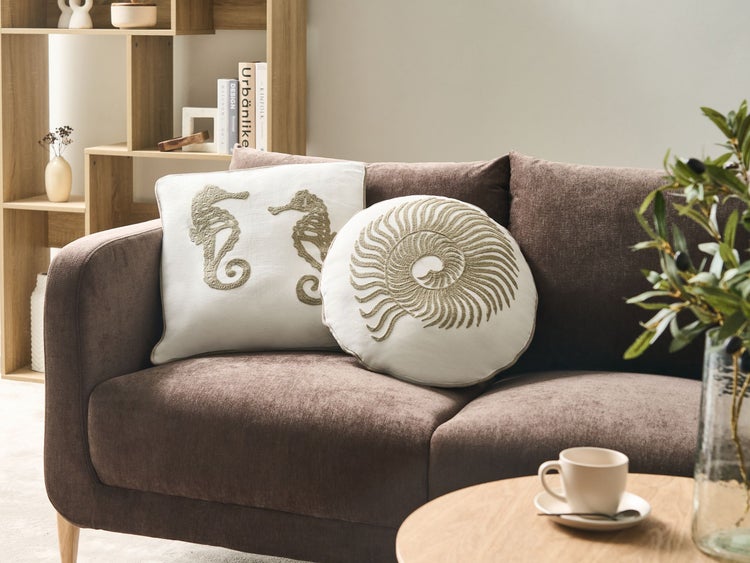 Dekoratives Wohnzimmer mit braunem Sofa und Zierkissen