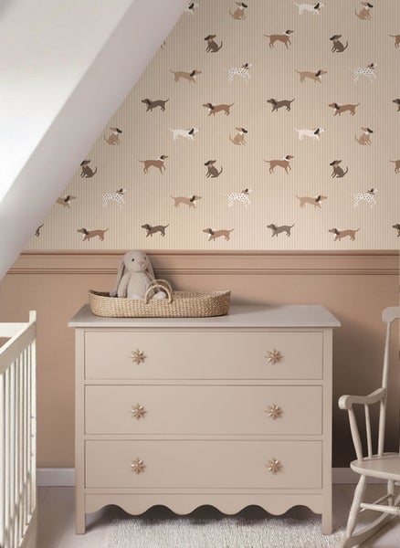 Ein Kinderzimmer mit einer Kommode, einem Schaukelstuhl und einer Tapete mit Hundemotiv.