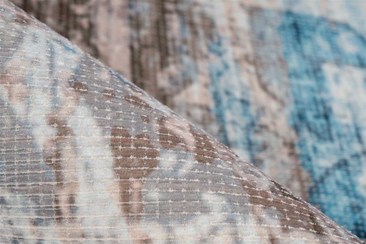 Nahaufnahme eines blau-braun gemusterten Teppichs im Vintage-Stil mit gewebter Textur und einer umgeknickten Ecke.