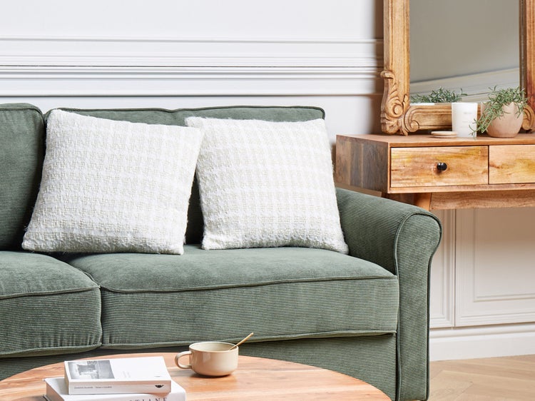 Wohnzimmer mit grünem Cordsofa und Dekokissen
