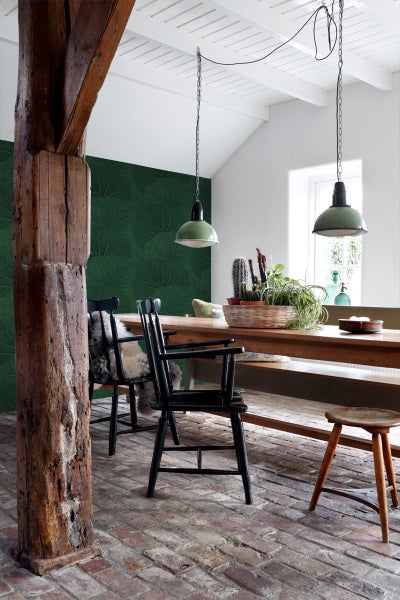 Esszimmer mit Holztisch, Stühlen und grüner Blattmuster-Tapete.