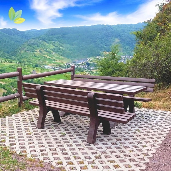 Sitzgruppe aus wetterfestem Material auf einem gepflasterten Platz mit Panoramablick auf eine Landschaft mit Bergen und Tal.