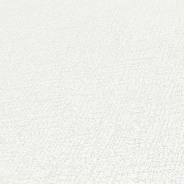 Helles Schlafzimmer mit Holzbett, Pflanze und Strohhut