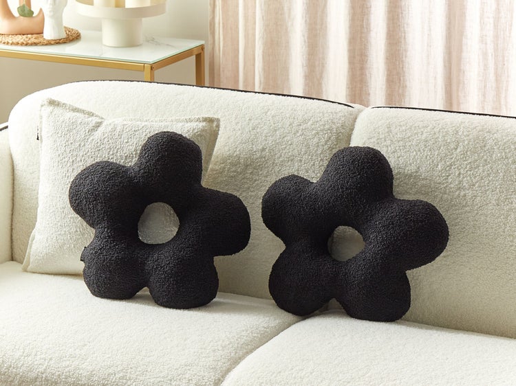 Dekorative schwarze Kissen in Blumenform auf einem Sofa