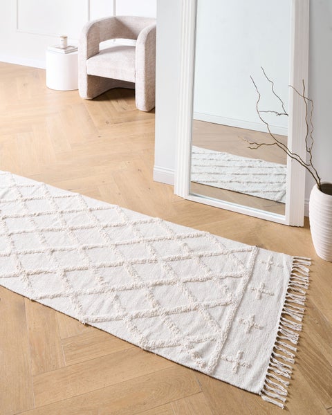 Szene mit einem hellen Teppichläufer mit Fransen und geometrischem Muster in einem modern eingerichteten Raum.