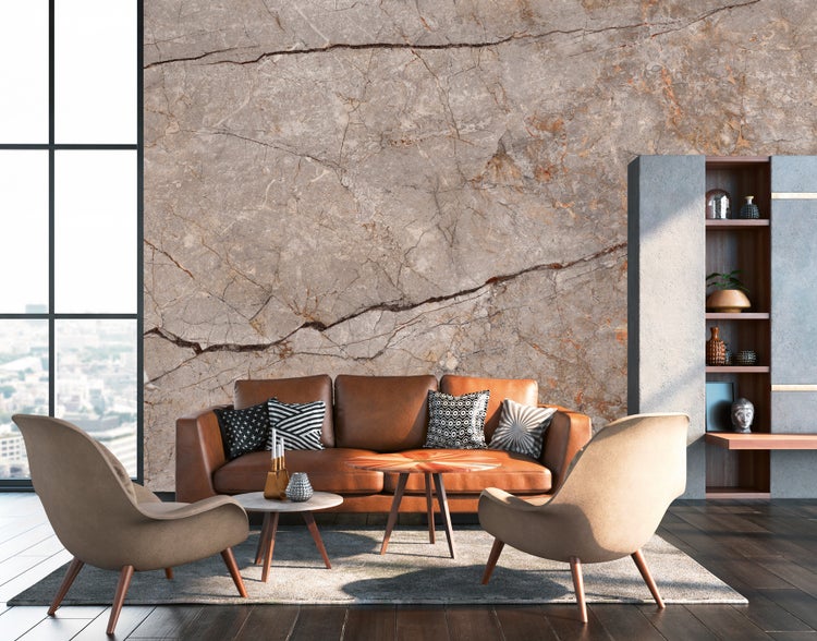 Wohnzimmer mit Ledersofa, Sesseln, Couchtischen und Bücherregal vor einer Marmorwand