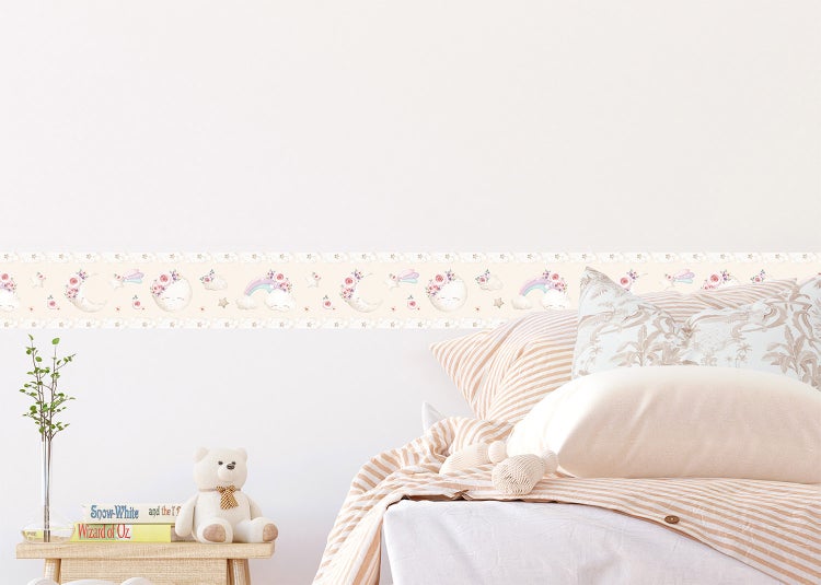 Selbstklebende Bordüre für das Kinderzimmer mit Mond, Regenbogen und Sternen in einem hellen, organisierten Zimmer über dem Bett.