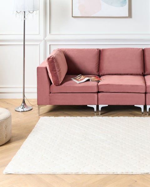 Wohnzimmer mit rosafarbenem Sofa, weißem Teppich und Stehlampe