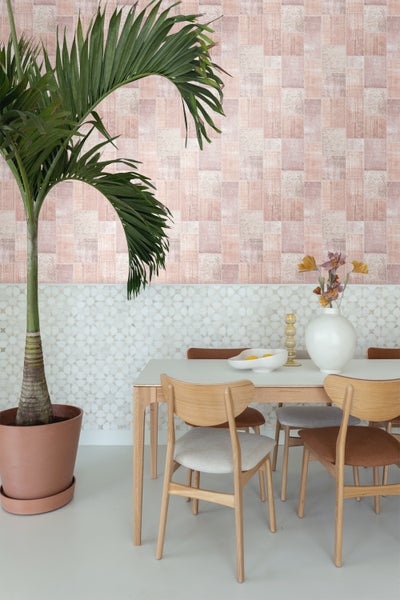 Esszimmer mit Esstisch, Stühlen, Pflanze im Topf und gemusterter Tapete.