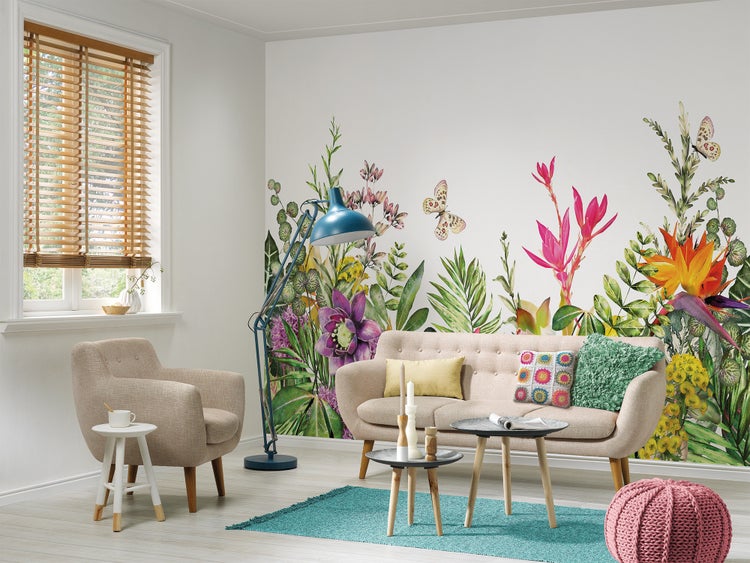 Hell eingerichtetes Wohnzimmer mit einer großflächigen Blumentapete, die bunte tropische Pflanzen, Blüten und Schmetterlinge zeigt.