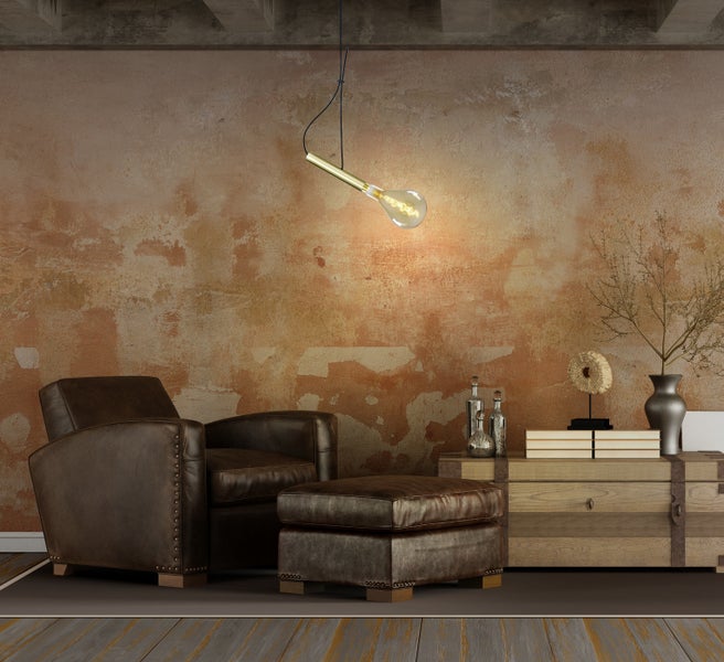 Wohnzimmer mit braunem Ledersessel, Hocker, Holztruhe und dekorativer Pendelleuchte