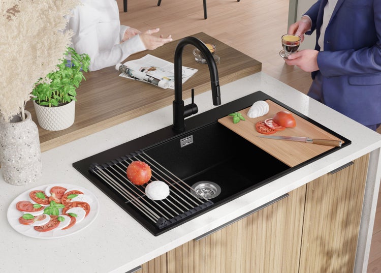 Schwarzes Spülbecken mit Abtropfgestell, Schneidebrett und Armatur in einer Küchenszene.