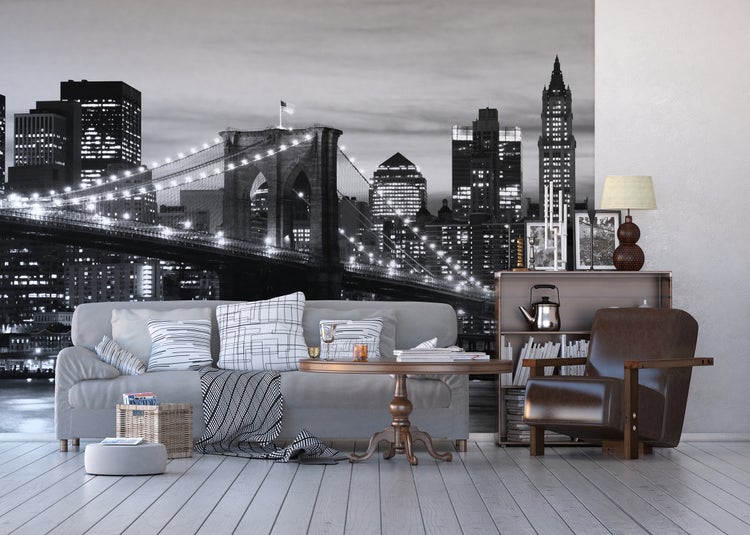 Wohnzimmer mit Fototapete einer Brücke bei Nacht, Sofa, Sessel und Tisch.