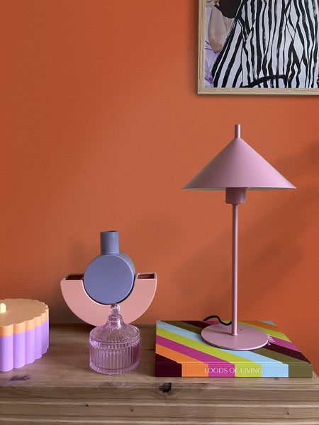 Modernes Esszimmer mit Wand aus terrakottafarbener Wandfarbe und gemusterten Fliesen, Holztisch mit Stühlen und einer großen Palme im Topf.