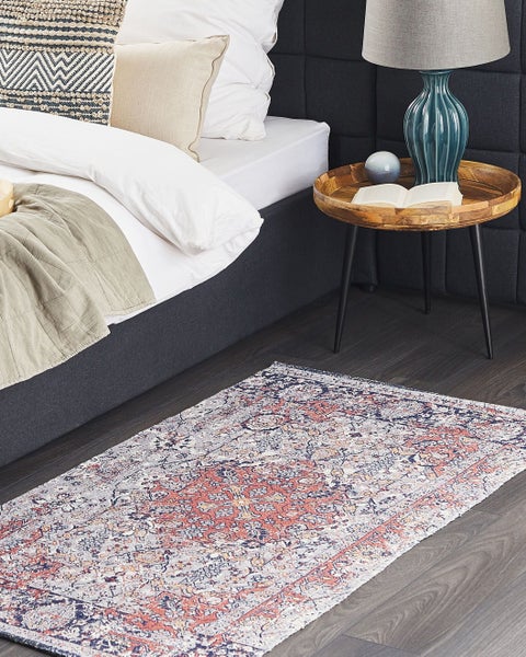 Teppich mit orientalischem Muster im Schlafzimmer neben einem Bett und Beistelltisch auf Boden in Holzoptik.