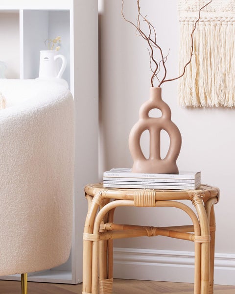 Dekorative Inneneinrichtung mit Rattantisch, Vase und Textilkunst