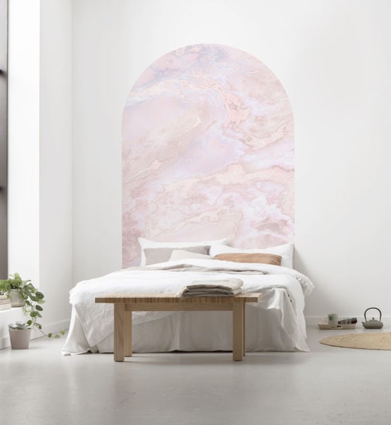 Schlafzimmer mit Marmor Wandtattoo in Bogenform, Bett und Holzbänken.