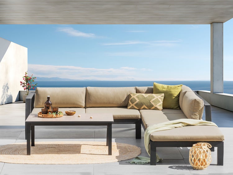 Gartenszene mit Lounge-Ecke, Tisch, Teppich und Dekoration auf einer Terrasse mit Meerblick