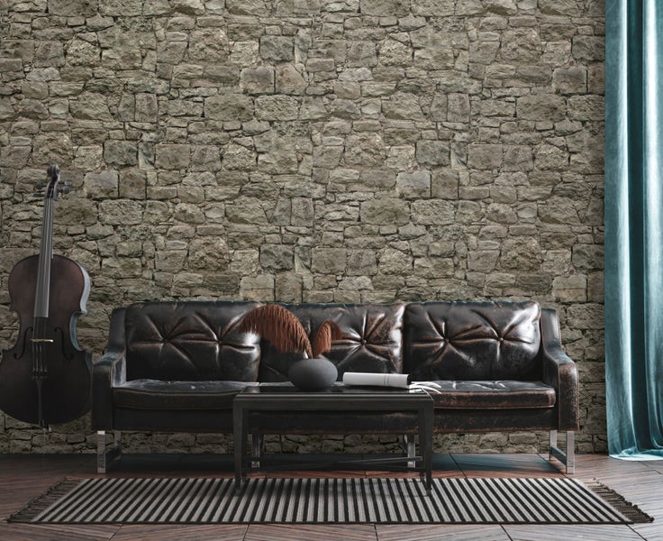 Wohnzimmer mit Ledersofa, Tisch, Cello und Steinwand