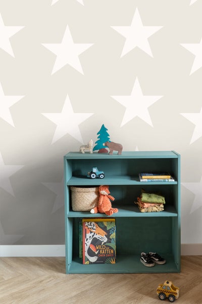 Regal im Kinderzimmer mit Spielzeug und Büchern vor einer Wand mit Sternenmuster.