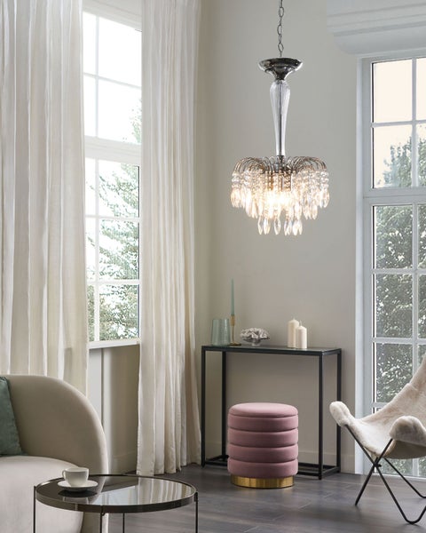 Wohnzimmer mit Kronleuchter, Tisch, Sessel und Fenstern