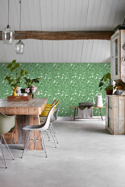 Heller Raum mit Holztisch, Stühlen und grüner Blättertapete.