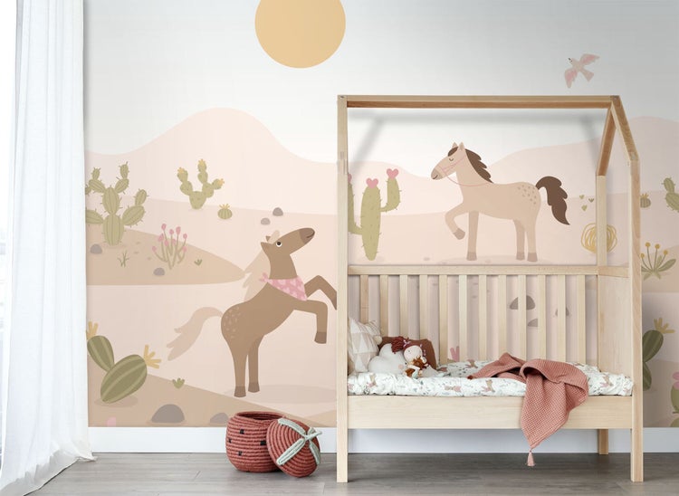 Kindertapete mit einer Wüstenlandschaft, Pferden und Kakteen hinter einem Hausbett aus Holz im Kinderzimmer.
