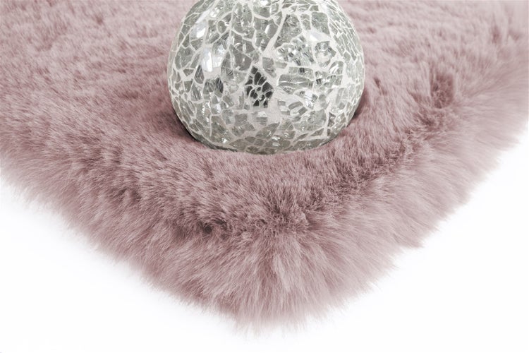 Rosa Kunstfellteppich mit einer dekorativen Mosaikkugel.