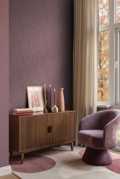 Wohnzimmer mit Kommode, Dekoration und Sessel auf einem gemusterten Teppich vor einer Wand mit Tapete.