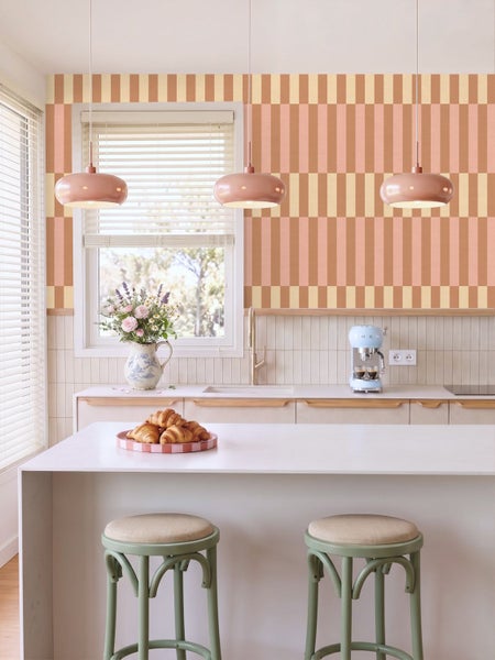 Geometrische Vliestapete mit Blockmuster in Erdtönen in einem hellen Kinderzimmer mit weißem Sideboard und Schreibtisch.