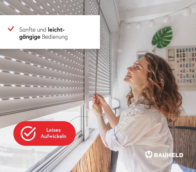 Eine Frau bedient einen Rollladen an einem Fenster in einem hellen Wohnraum.