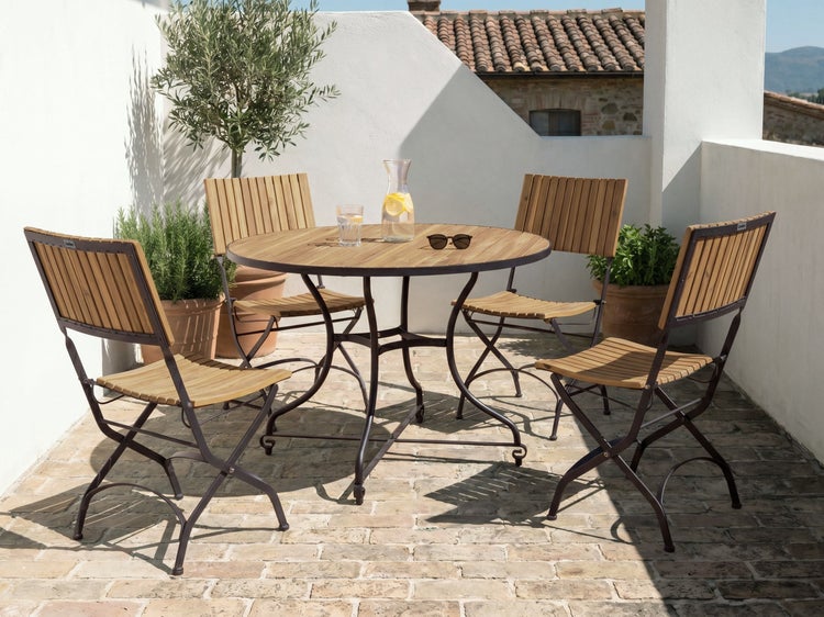 Gartenmöbel-Set bestehend aus einem runden Tisch und vier Klappstühlen mit Metallgestell und Holzlatten auf einer hellen Steinterrasse.