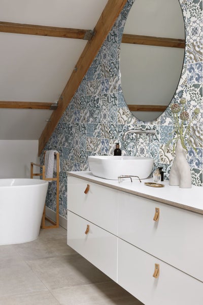 Badezimmer mit freistehender Badewanne, Waschtischunterschrank und gemusterten Fliesen