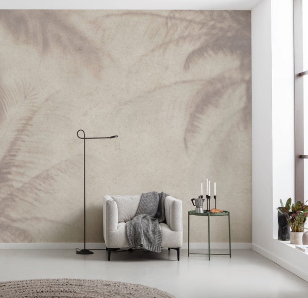 Wohnzimmer mit Sessel, Stehlampe und Beistelltisch vor einer Wand mit Palmenmuster