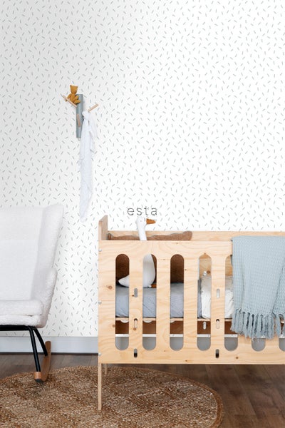 Kinderzimmer mit Kinderbett, Schaukelstuhl und gemusterter Tapete