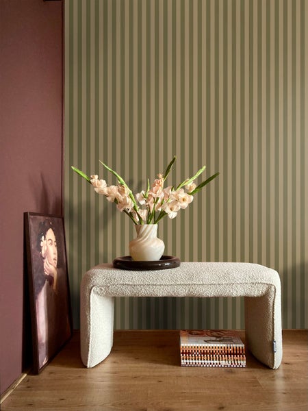 Dekoratives Interieur mit gestreifter Tapete, Bank, Blumenvase und gerahmtem Bild