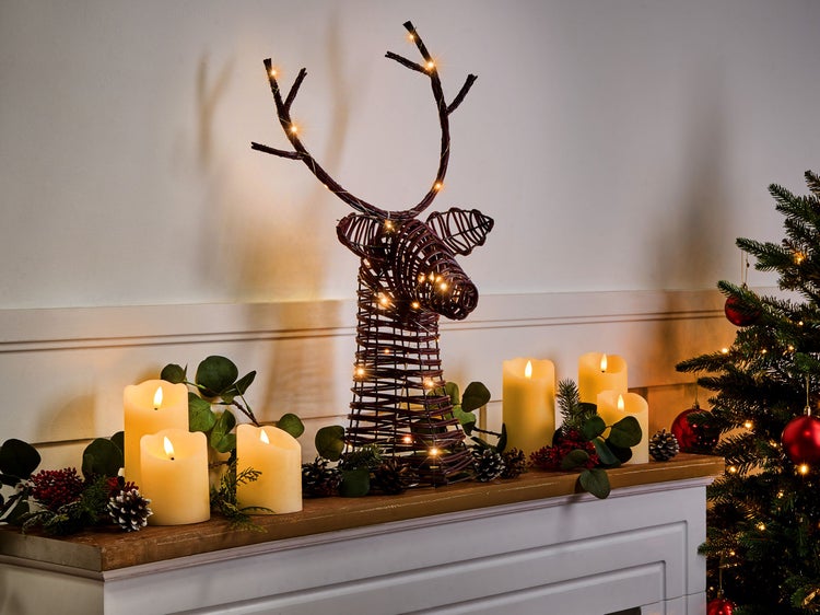 Dekoratives Arrangement mit einem beleuchteten Rentier aus Weide, LED-Kerzen, Tannenzapfen und einer Tanne.