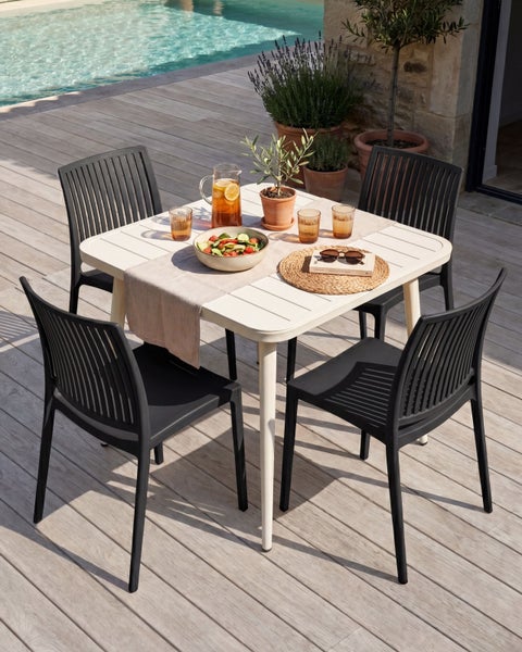 Gartenmöbel-Set mit einem quadratischen Tisch und vier schwarzen Stühlen auf einer Holzterrasse an einem Pool.