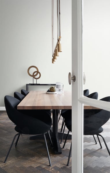 Esszimmer mit Holztisch, Stühlen, Hängelampe und dekorativen Elementen auf einem Sideboard