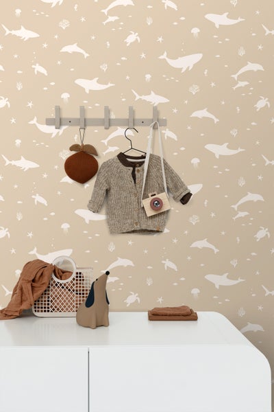 Ein Wickeltisch mit Wickelauflage, einem Spiegel und einem Stofftier in einem Kinderzimmer mit Tiermotiven an der Wand.