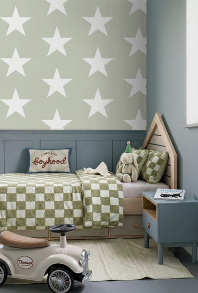 Kinderzimmer mit Sternentapete, blauer Wandtäfelung, Holzbett in Hausform mit karierter Bettwäsche und Spielzeugauto im Retro-Stil.