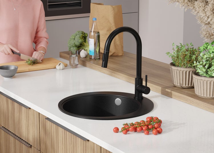 Schwarzes Spülbecken mit Armatur auf einer Küchentheke mit Lebensmitteln