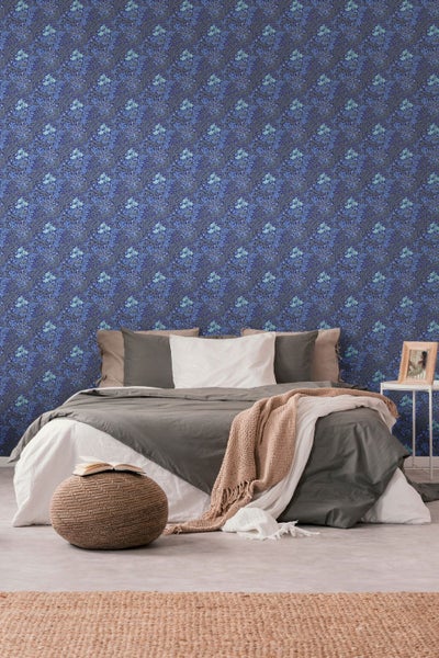 Nahaufnahme eines Schreibtisches mit floraler Tapete, Uhr, Stiften und Notizblock