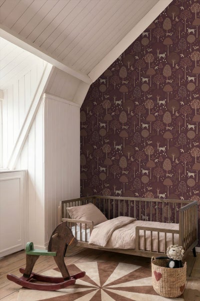 Kinderzimmer mit gemusterter Vliestapete mit Waldmotiv, Bäumen und Hunden, einem hölzernen Kinderbett und einem Schaukelpferd.