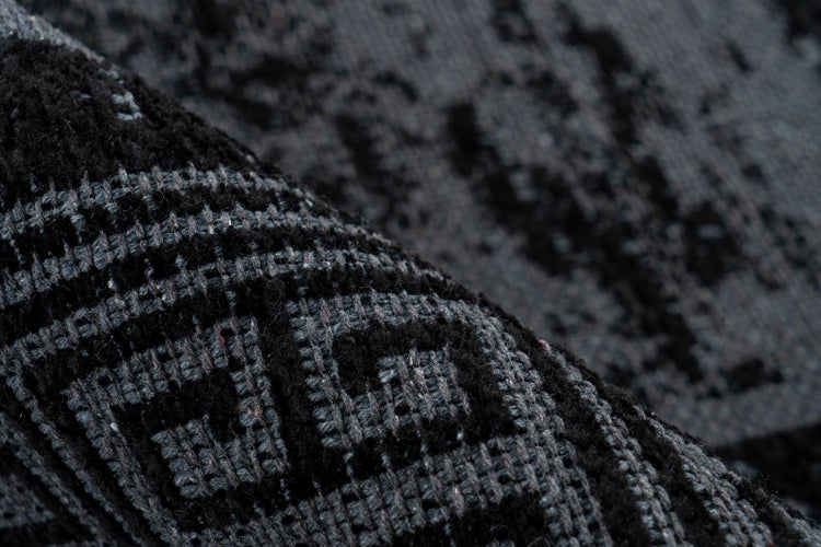 Nahaufnahme eines Teppichs mit geometrischem Muster und strukturierter Oberfläche.